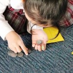 Young girl counting coins on blue carpet